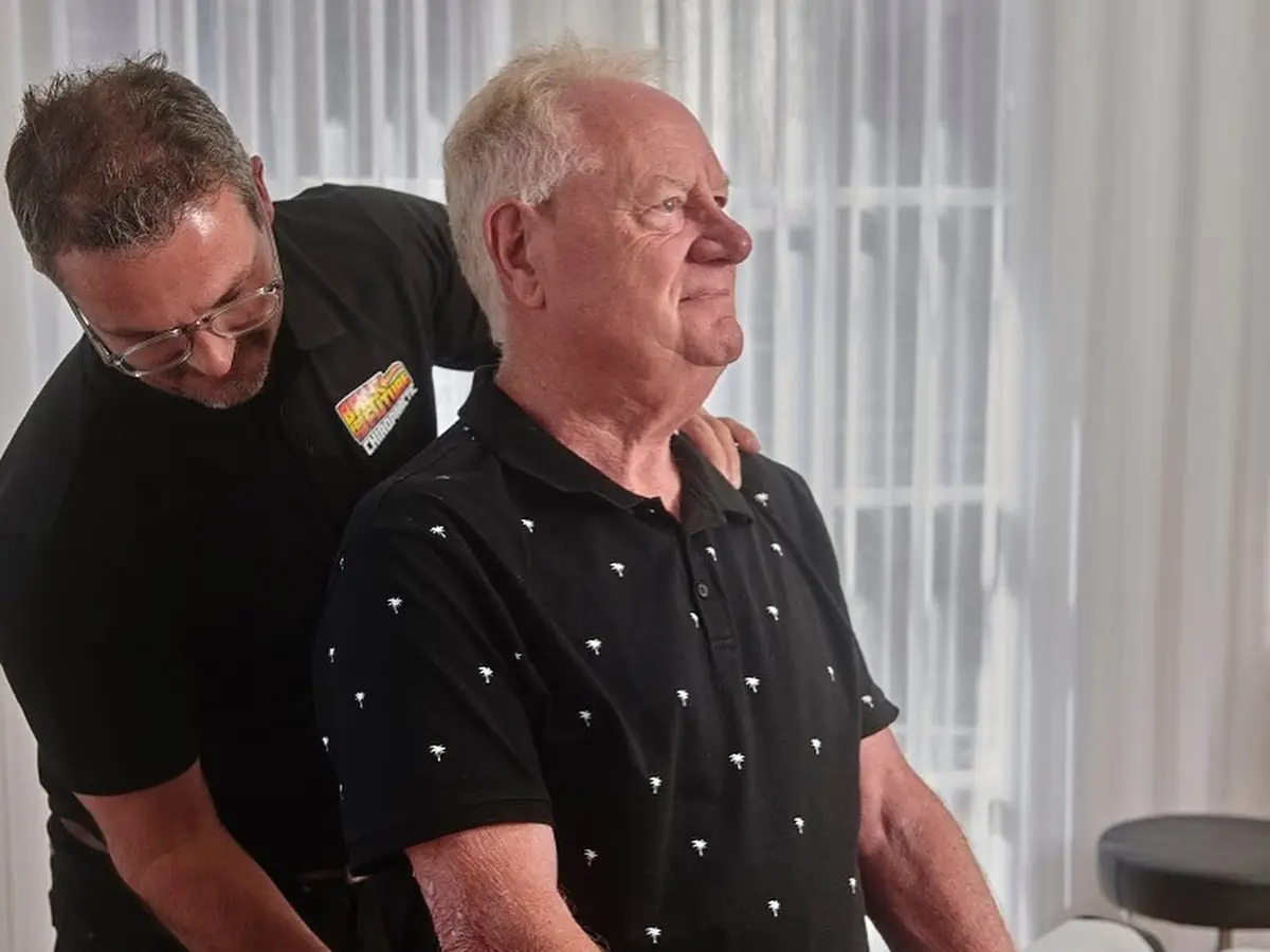 Chiropractor assessing an older patient's spine